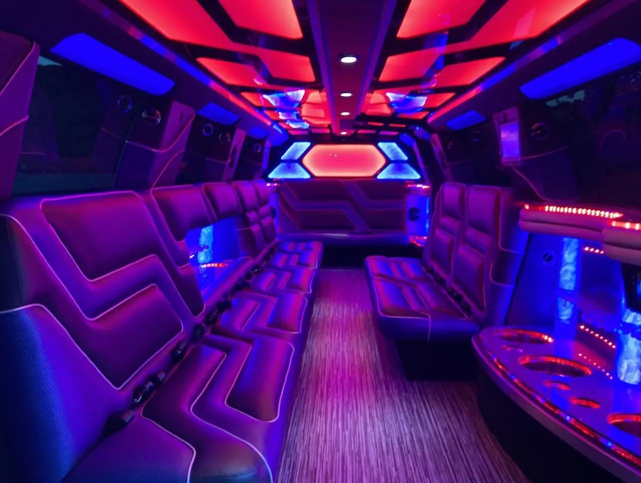 Interior of Cadillac Escalade Stretch Limousine with red and blue LED lights, luxury leather seating, and party-ready ambiance by Basking Ridge Limousine Services.