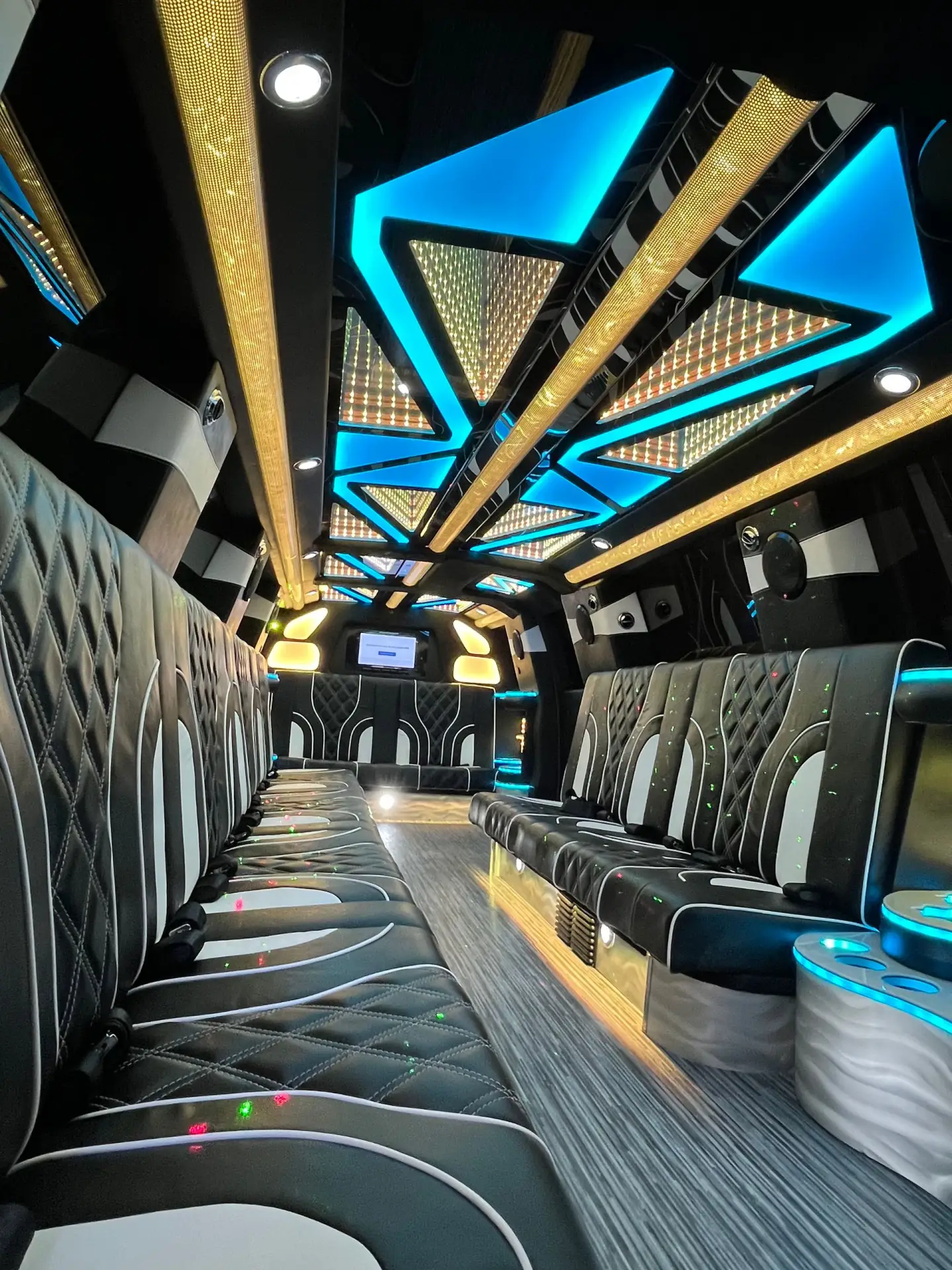 Interior of Basking Ridge Limousine's 2025 GMC Yukon Stretch Limo featuring black diamond-stitched leather seating, blue LED ceiling lights, and luxury party-style ambiance.