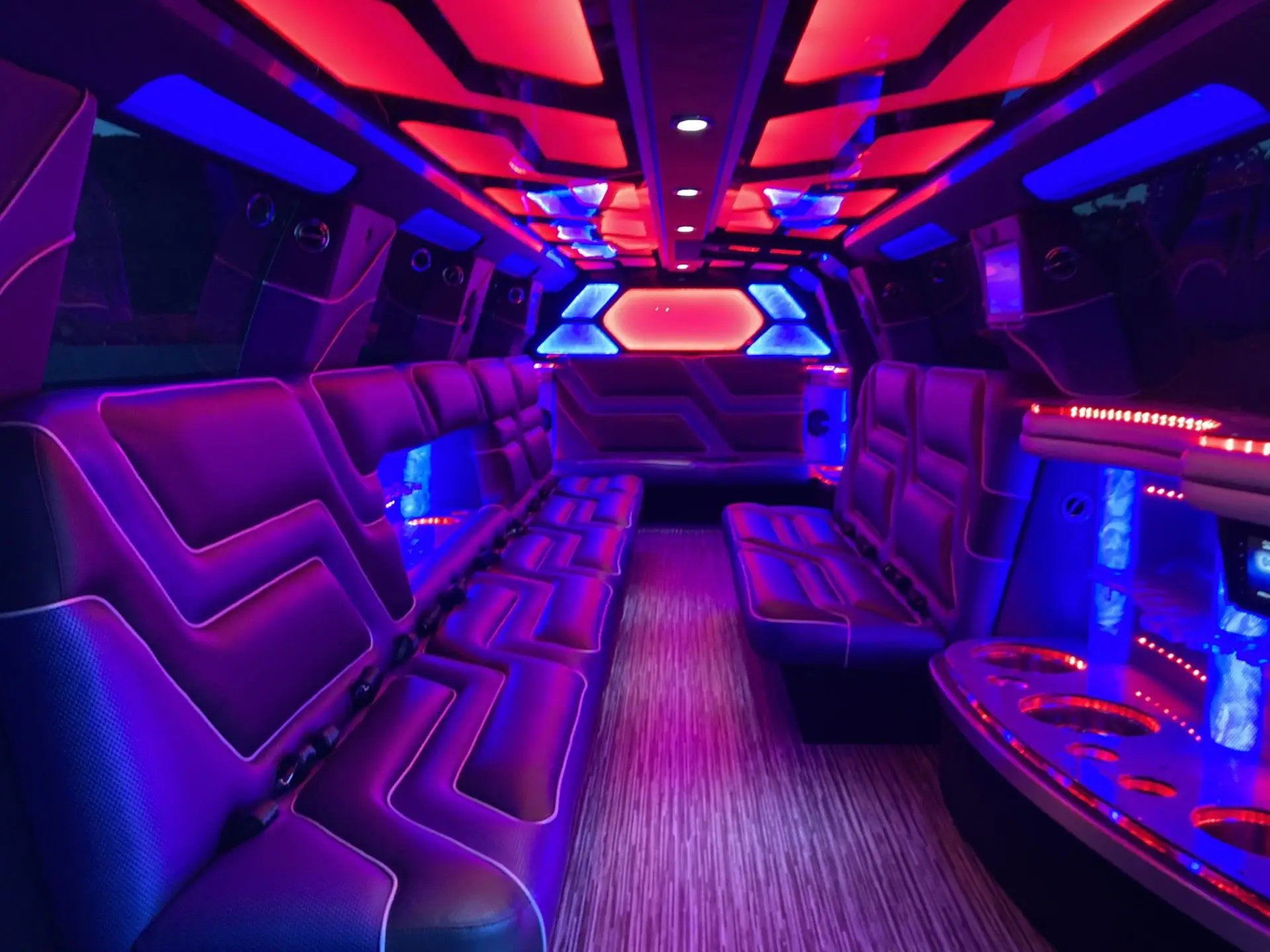 Interior of Cadillac Escalade Stretch Limousine with red and blue LED lights, luxury leather seating, and party-ready ambiance by Basking Ridge Limousine Services.