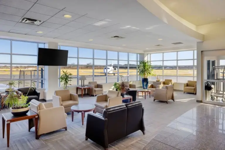 Luxury passenger lounge inside Morristown Municipal Airport (MMU) with runway views and a private jet visible outside the large windows.