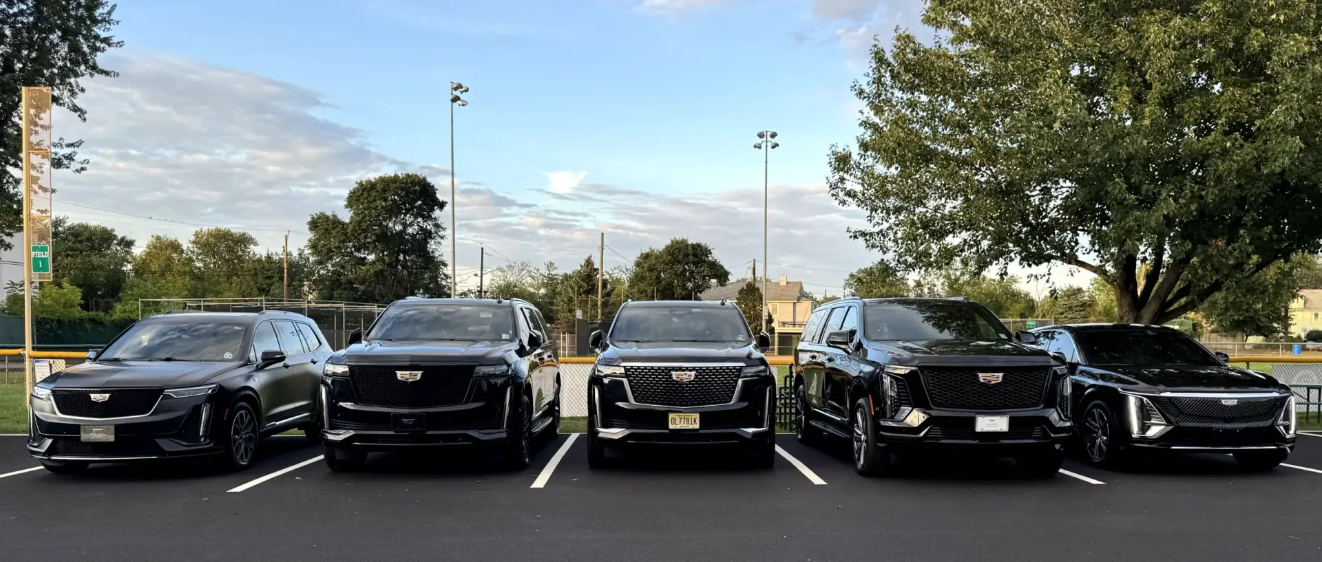 Lineup of five black Cadillac SUVs from the Basking Ridge Limousine fleet at golden hour โ National Limousine Association member with a 450+ city affiliate network