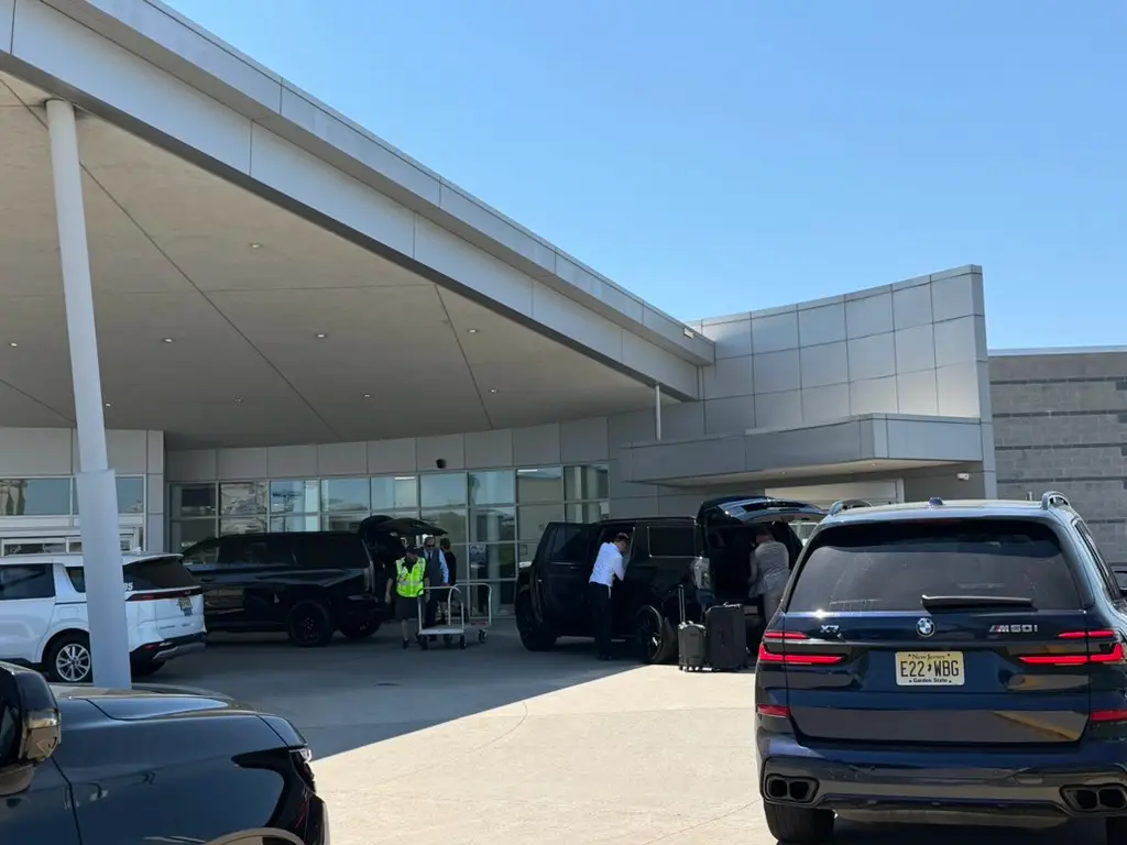 Black Cadillac Escalade and chauffeur loading luggage at a New Jersey FBO entrance with ground staff assisting โ Basking Ridge Limousine private aviation FBO coordination