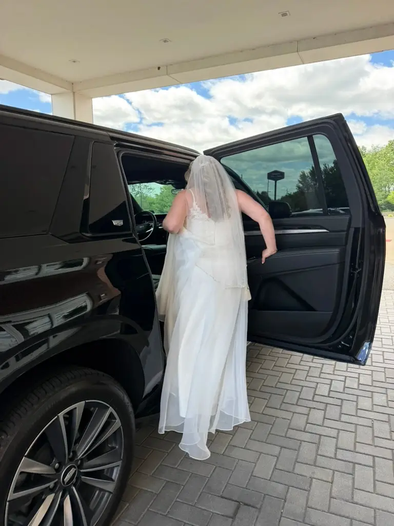 Bride entering chauffeured Cadillac Escalade for her New Jersey wedding — luxury wedding limo service by Basking Ridge Limousine