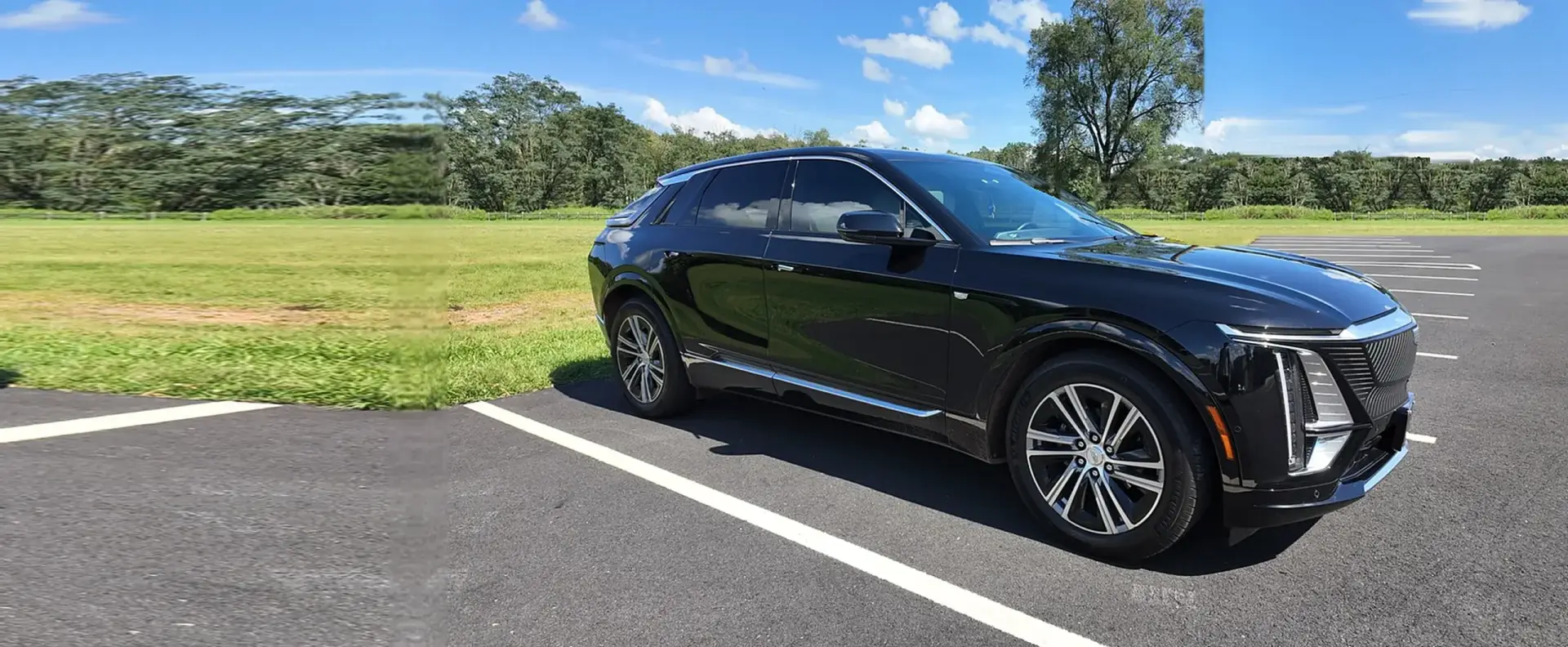 Black 2025 Cadillac LYRIQ EV parked on asphalt beside an open field, used for chauffeured electric car service by Basking Ridge Limousine Services in New Jersey