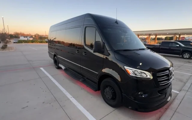 Black high-roof Mercedes-Benz Sprinter party bus photographed at sunset, showing its long wheelbase, chrome grille and side entry step