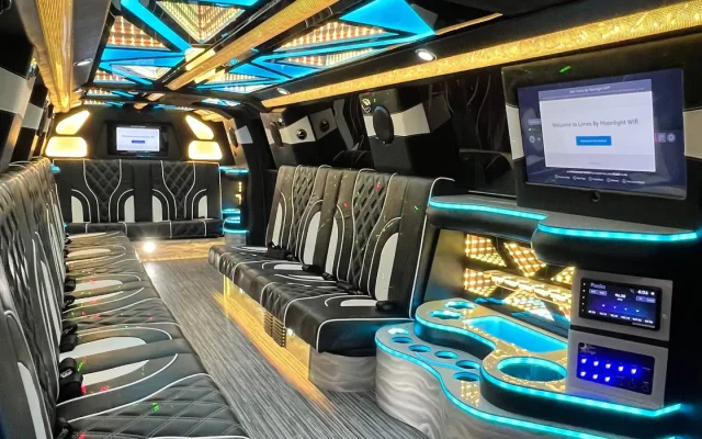 Interior of Basking Ridge Limousine’s 2025 GMC Yukon Stretch featuring plush black and white leather seating, golden and blue LED ceiling lights, and a custom bar area.
