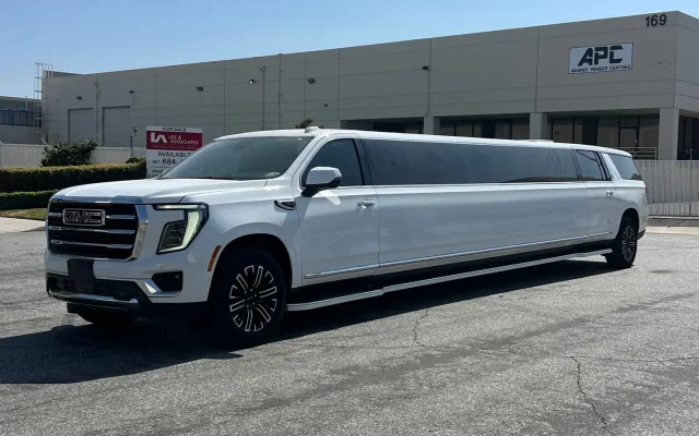 Basking Ridge Limousine’s white 2025 GMC Yukon Stretch Limousine parked in front of an industrial building under a clear blue sky.