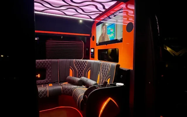 Interior of 2025 Mercedes Sprinter Maybach limo party bus showing Maybach illuminated floor entry, orange LED lighting, diamond-stitched leather seating and LCD screen — Basking Ridge Limousine NJ