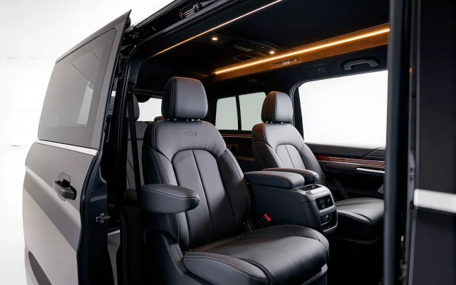Black leather interior of a 14 passenger Ford Transit van with captain's seats, high-top headroom and ambient lighting